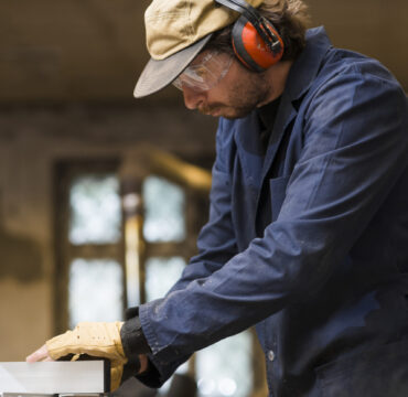 portrait-male-carpenter-wearing-ear-defender-working-workshop